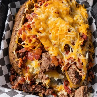 SteakFlo baked potato loaded with seasoned steak, bacon and cheese