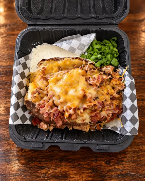Baked potato loaded with bacon, chicken, melted cheese and ranch, served with green onions