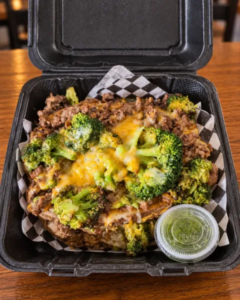 Baked potato loaded with seasoned steak, fresh broccoli and melted cheese