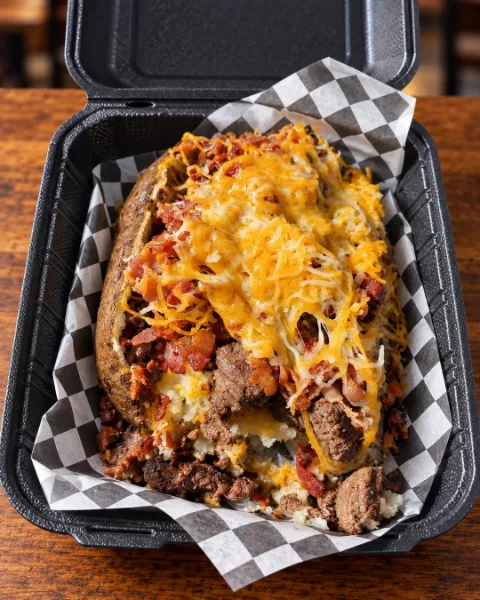 SteakFlo baked potato topped with seasoned steak, crispy bacon and shredded cheese